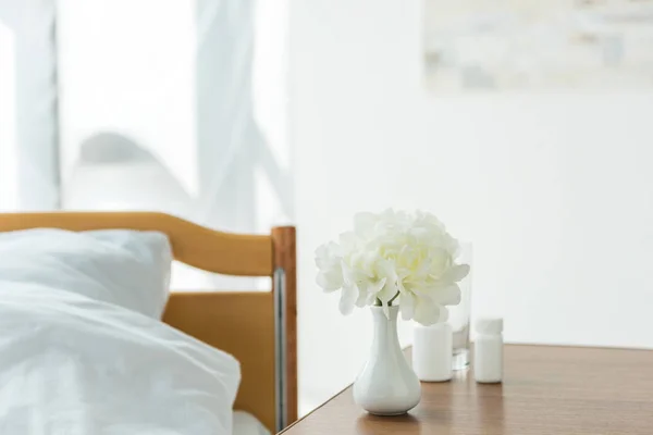 Foyer sélectif de vase avec des fleurs et des bouteilles avec des pilules dans la chambre — Photo de stock