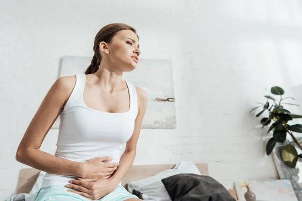 Low angle view of stressed young woman with stomach ache — Stock Photo
