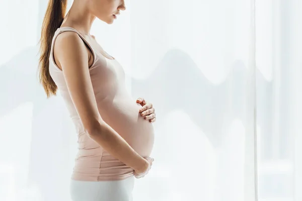 Vista recortada de la mujer embarazada tocando el vientre en casa - foto de stock