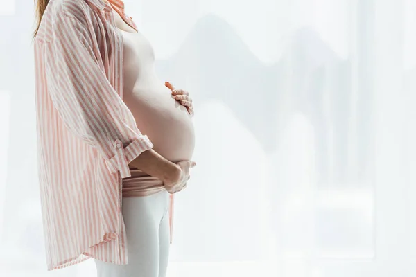 Vista ritagliata della donna incinta che tocca la pancia a casa — Foto stock