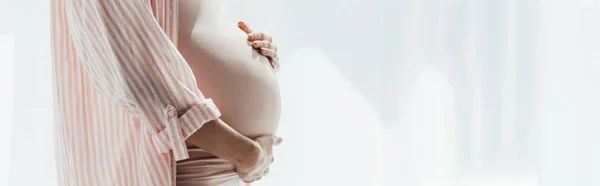 Plano panorámico de la mujer embarazada en camisa rayada tocando el vientre - foto de stock