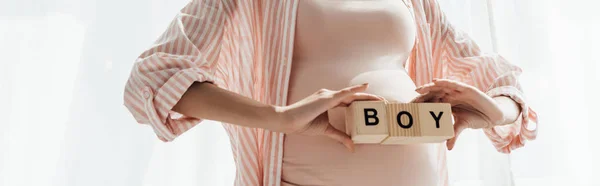 Panoramic shot of pregnant woman holding wooden blocks with word boy — Stock Photo