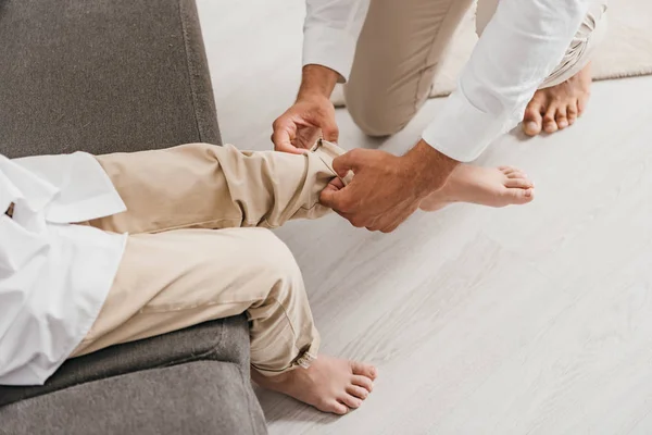 Cropped view of father helping son to get dressed at home — Stock Photo