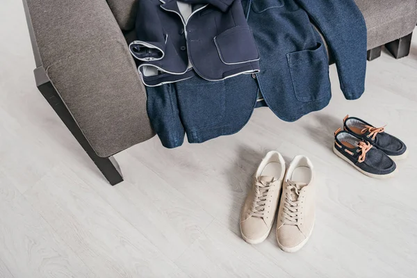 Formal jackets on sofa and shoes on floor at home — Stock Photo