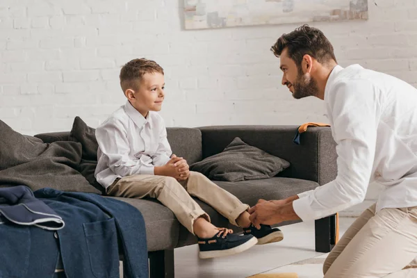 Padre barbuto allacciatura lacci per scarpe per il figlio a casa — Foto stock