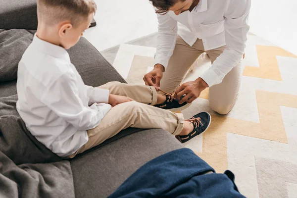 Cropped view of father tying shoelaces for son at home — Stock Photo