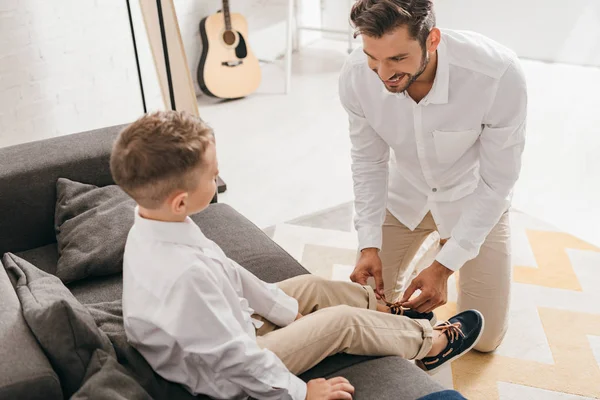 Père barbu attacher lacets pour fils à la maison — Photo de stock