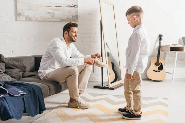 Fils regarder père alors qu'il attacher lacets à la maison — Photo de stock