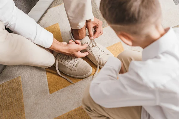 Teilansicht von Vater lehrt Sohn Schnürsenkel zu Hause zu binden — Stockfoto