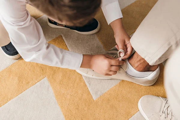 Visão parcial do pai ensinando filho a amarrar cadarços em casa — Fotografia de Stock