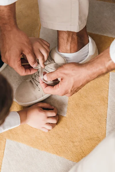 Ausgeschnittene Ansicht von Vater lehrt Sohn Schnürsenkel zu Hause zu binden — Stockfoto