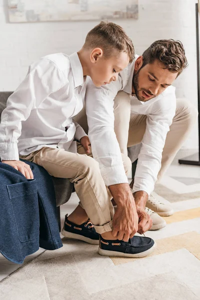 Father teaching son to tying shoelaces at home — Stock Photo