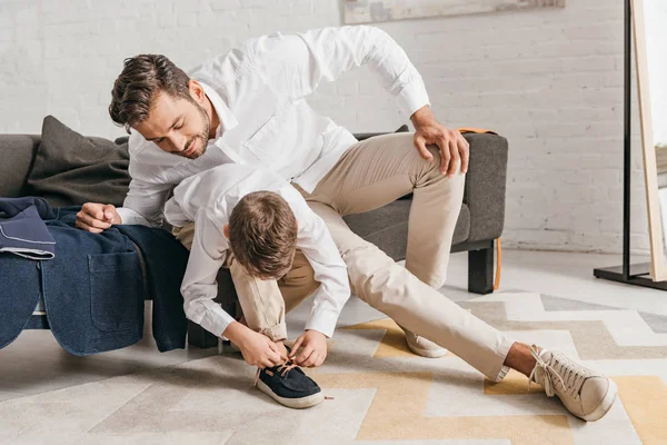 Pai ensinando filho a amarrar cadarços em casa — Fotografia de Stock