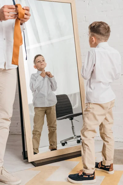 Vista parziale di padre e figlio in camicie bianche vestirsi vicino allo specchio — Foto stock