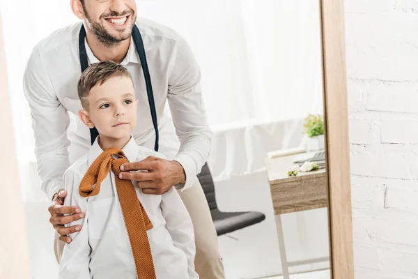 Partial view of father and son in white shirts getting dressed near mirror — Stock Photo