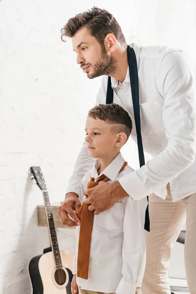 Bearded dad helping son with tie at home — Stock Photo
