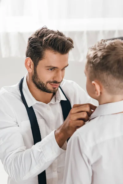 Smiling father helping son to get dressed at home — Stock Photo