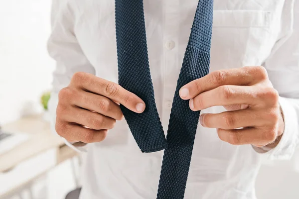 Partial view of man in white shirt tying tie — Stock Photo