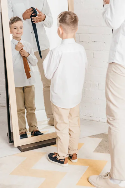 Visão parcial do pai e do filho em camisas brancas com laços perto do espelho — Fotografia de Stock