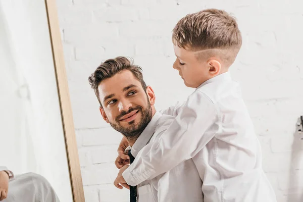 Fröhlicher Junge umarmt bärtigen Papa im weißen Hemd zu Hause — Stockfoto