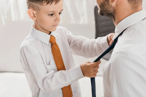 Recortado vista de hijo en camisa blanca ayudar a papá con corbata en casa - foto de stock