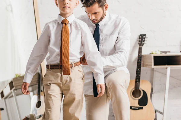Бородатий батько допомагає синові одягатися вдома — стокове фото