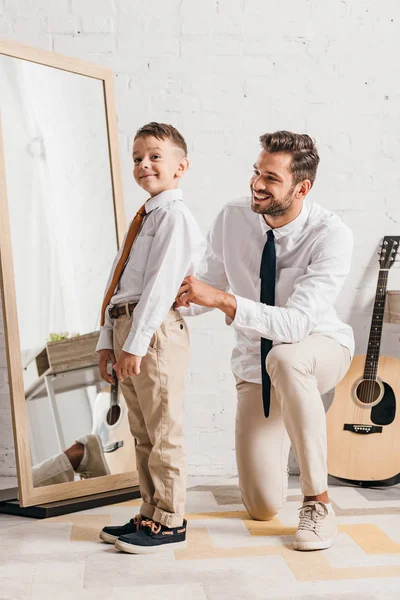 Bearded dad helping son to get dressed at home — Stock Photo