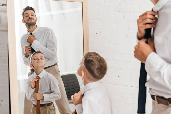 Son and dad in formal wear standing near mirror at home — Stock Photo