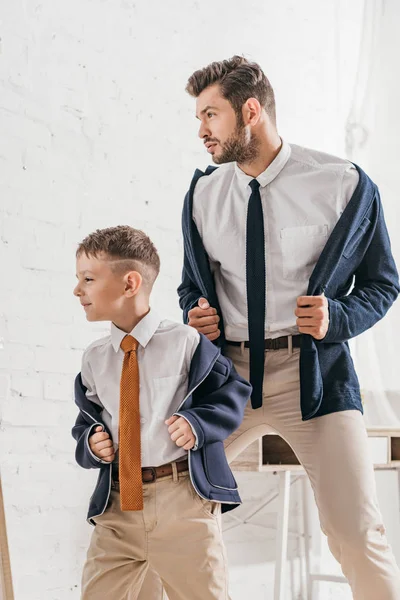 Padre seguro de sí mismo y su hijo en ropa formal en casa - foto de stock