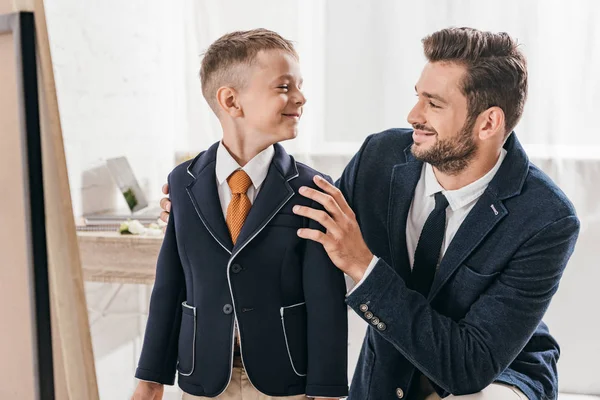 Confident dad and son in formal wear looking at each other at home — Stock Photo