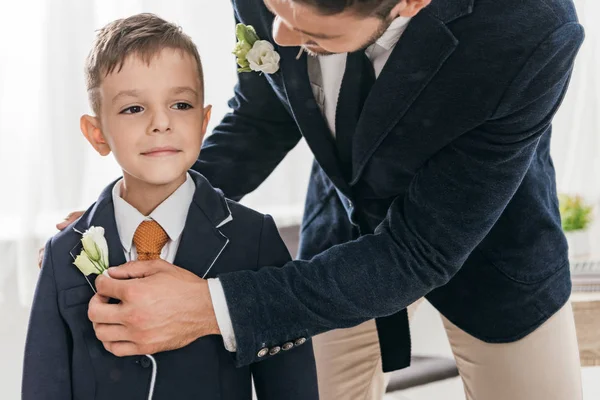 Cropped view of dad and son in jackets with boutonnieres — Stock Photo