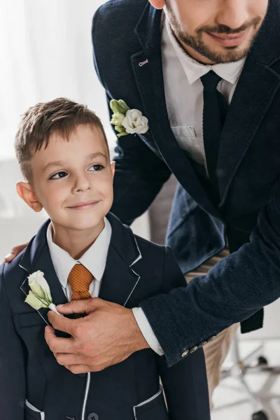 Cropped view of dad and son in jackets with boutonnieres — Stock Photo