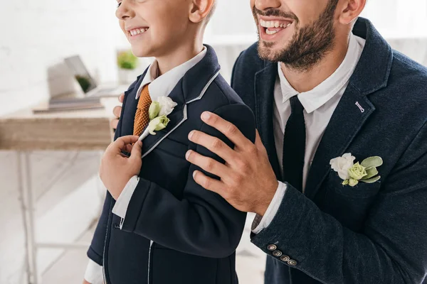 Vista parcial de hijo y papá en chaquetas con boutonnieres - foto de stock