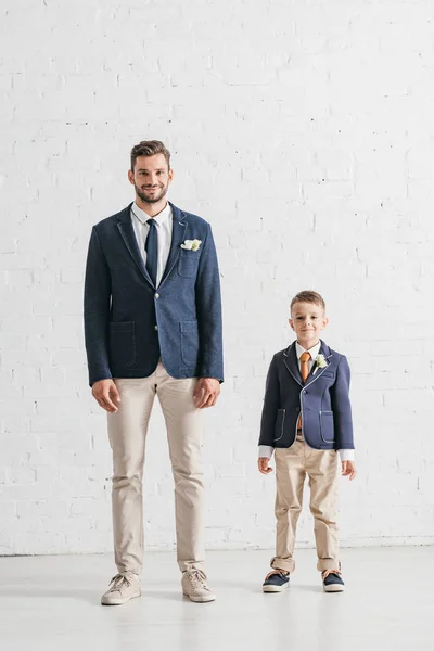 Full length view of father and son in jackets with boutonnieres — Stock Photo