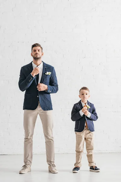 Полный вид на отца и сына в куртках с бутоньерками — стоковое фото