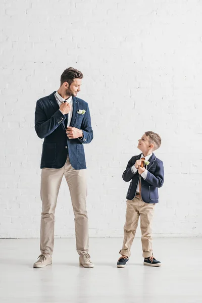 Vue pleine longueur du père et du fils en vestes avec boutonnières se regardant — Photo de stock