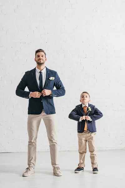Повнометражний вид батька і сина в куртках з бутоньєрами — стокове фото