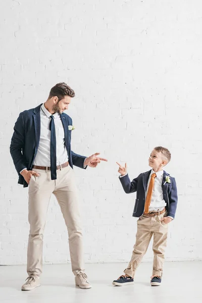 Vue pleine longueur du père et du fils en vestes avec boutonnières se regardant — Photo de stock