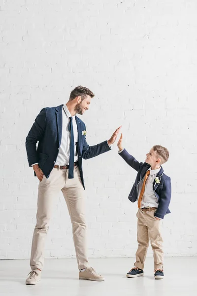 Piena vista lunghezza di padre e figlio in giacche con boutonnieres guardando l'un l'altro — Foto stock
