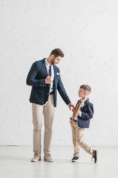 Ganzheitliche Ansicht von Vater und Sohn in Jacken mit Boutonnieres, die sich gegenseitig anschauen — Stockfoto