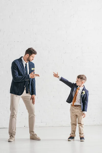 Ganzheitliche Ansicht von Vater und Sohn in Jacken mit Boutonnieres, die sich gegenseitig anschauen — Stockfoto