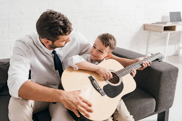 Тато навчає сина грати на акустичній гітарі вдома — стокове фото
