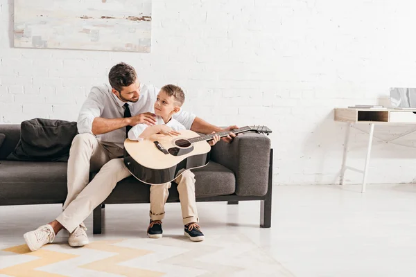 Dad teaching son to play acoustic guitar at home — Stock Photo