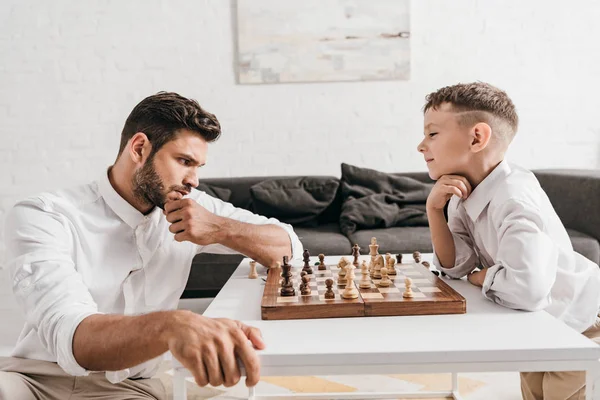 Pai e filho jogando xadrez juntos em casa — Fotografia de Stock