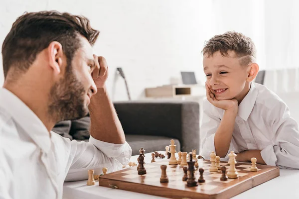 Padre e hijo jugando ajedrez juntos en casa - foto de stock