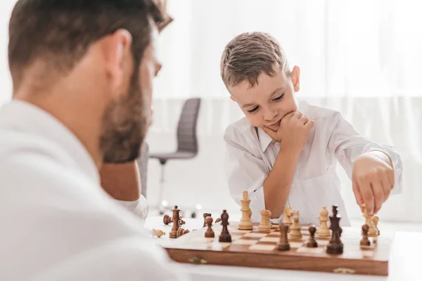 Enfoque selectivo de papá e hijo jugando ajedrez juntos en casa - foto de stock