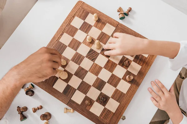 Vue recadrée de papa et fils jouant aux échecs ensemble à la maison — Photo de stock