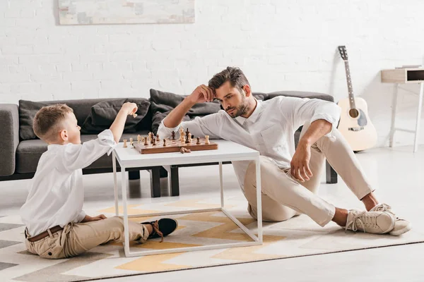 Папа и сын играют вместе в шахматы дома — стоковое фото