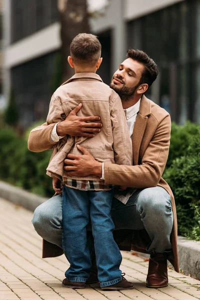 Feliz padre abrazando hijo en la calle en el día de otoño - foto de stock