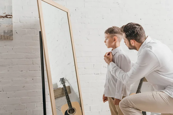 Padre aiutare il figlio a vestirsi vicino specchio — Foto stock